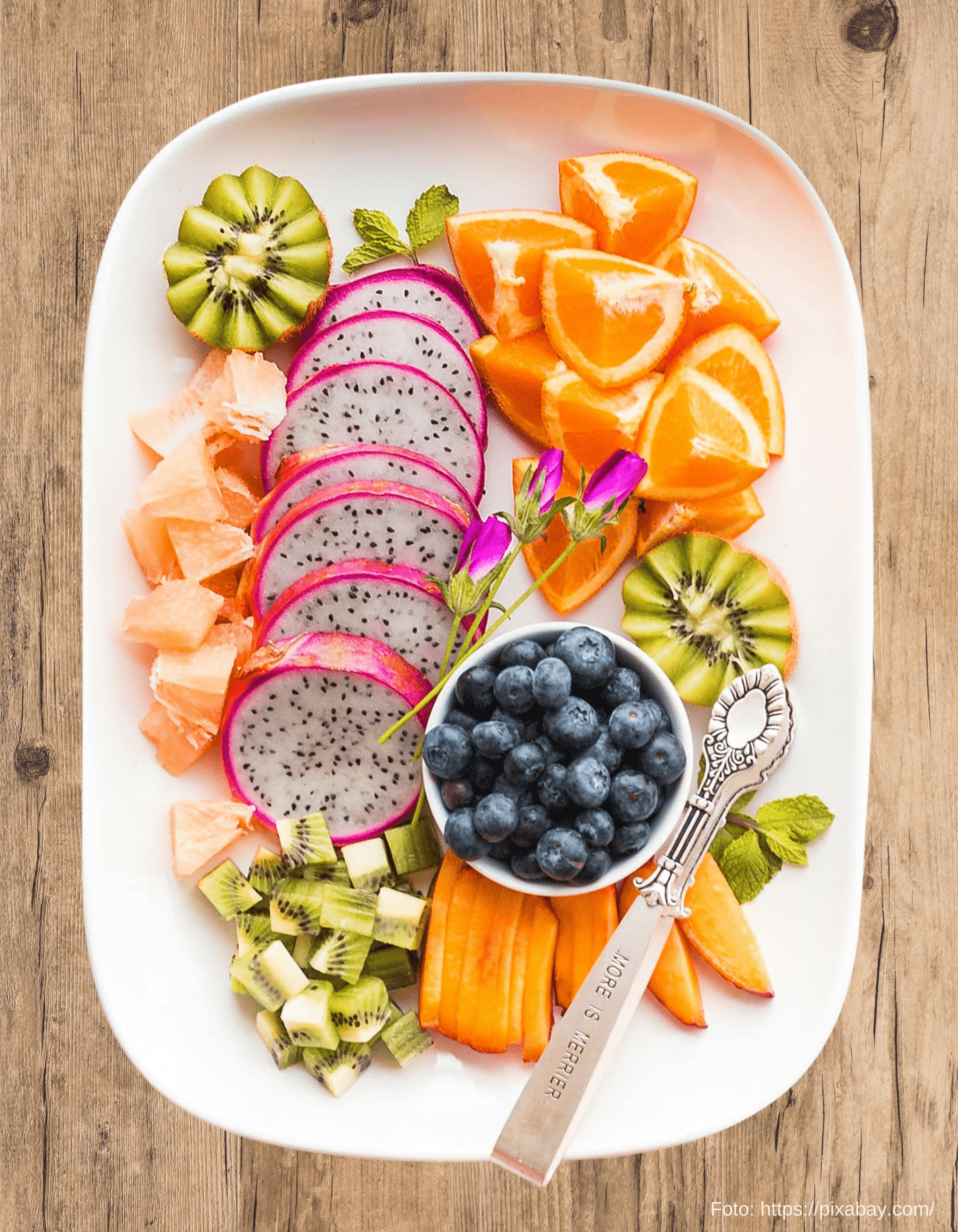 Bunte Obstplatte mit Drachenfrucht, Kiwi, Orange und Heidelbeeren dekorativ auf einem Teller angerichtet