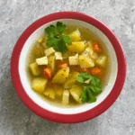 Teller mit dampfender veganer Kartoffelsuppe und Räuchertofu