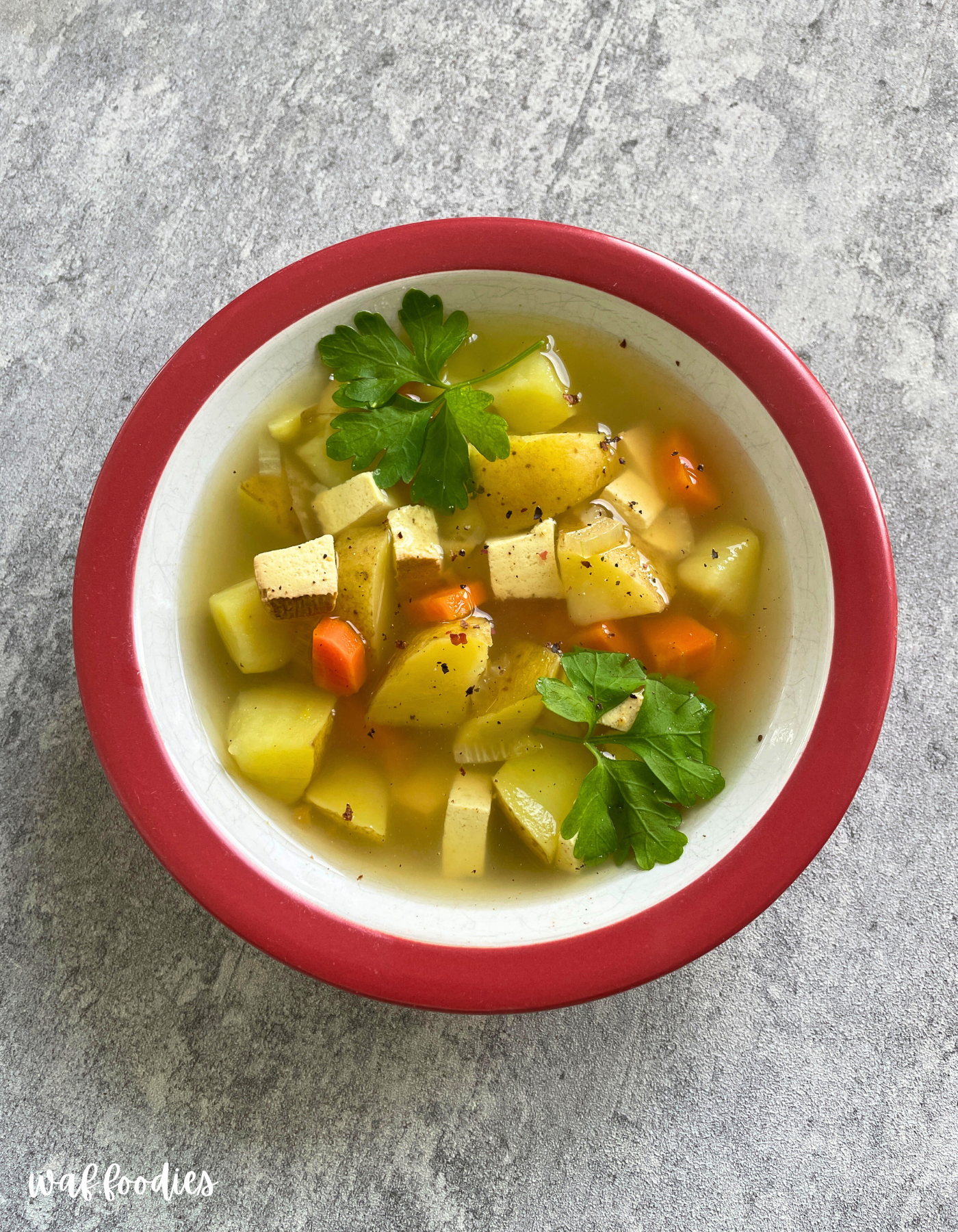 Teller mit dampfender veganer Kartoffelsuppe und Räuchertofu