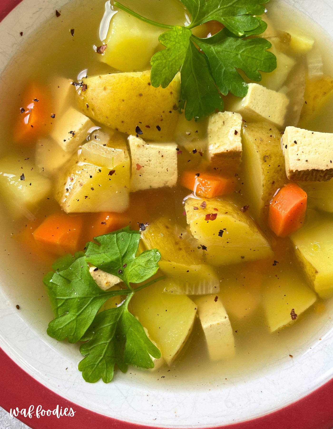 Zutaten auf einem Schneidebrett: Karotten, Zwiebel, Tofu, Kartoffeln