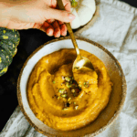 Suppenschale mit goldgelber Kürbissuppe und Löffel