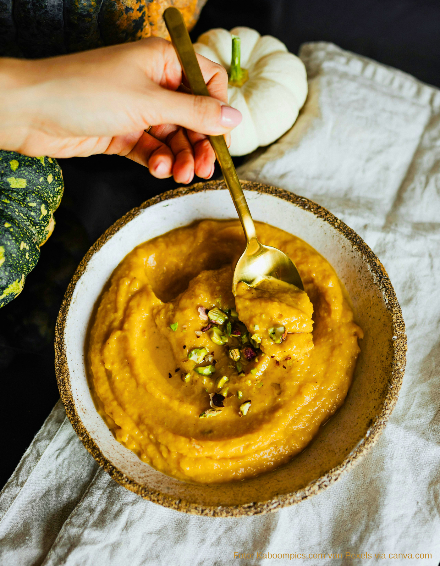 Suppenschale mit goldgelber Kürbissuppe und Löffel