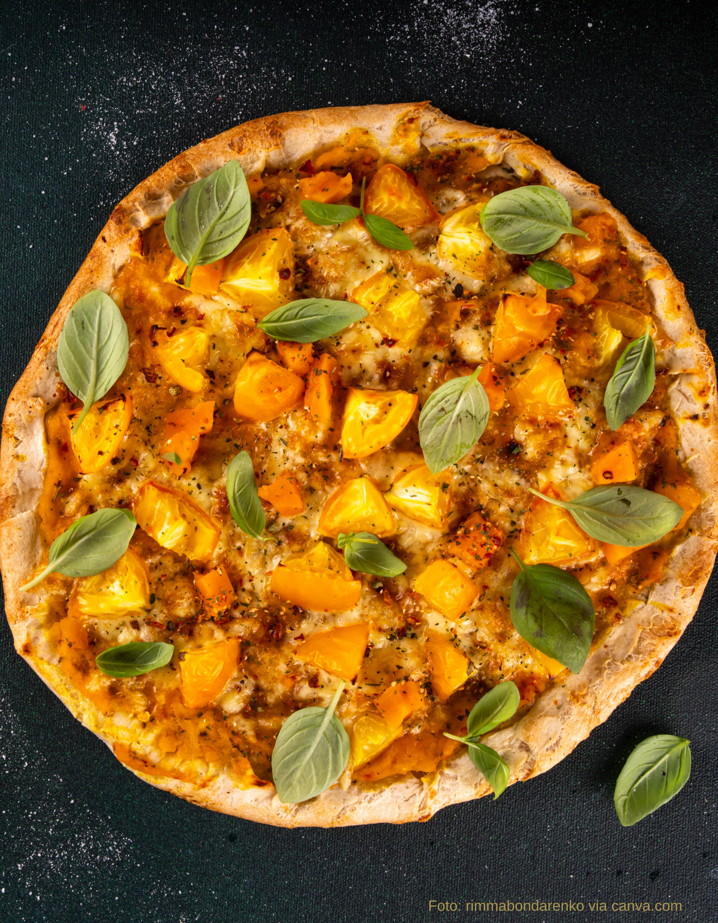 Pizza mit Tomaten, Kürbiswürfeln und veganem Käse vor dem Backen