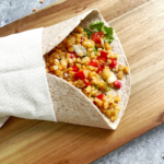 Aufgeschnittener Wrap mit roter Linsenfüllung und cremiger Sojajoghurt Sauce