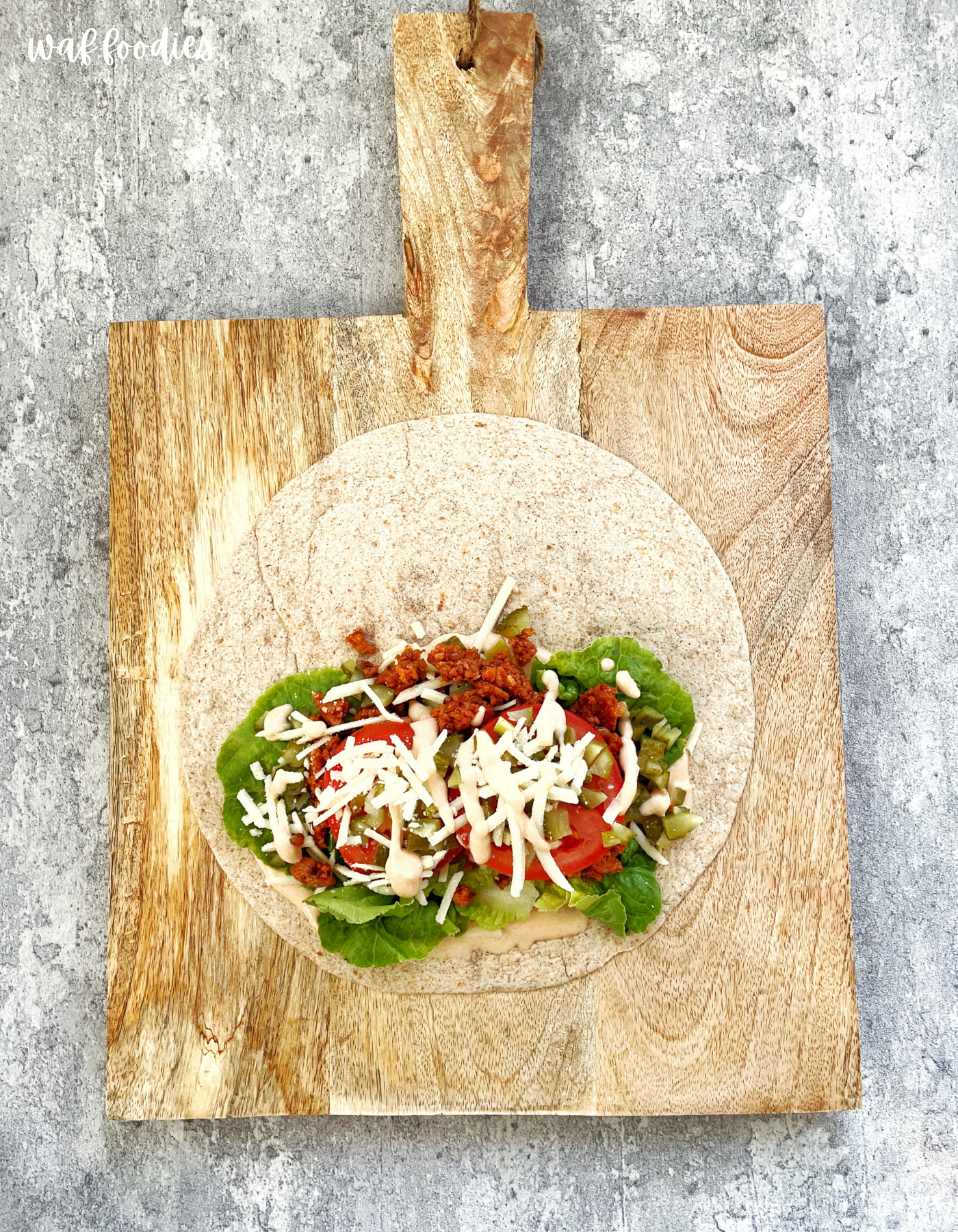 Veganer Cheeseburger Wrap halbiert auf einem Teller mit Burgersauce